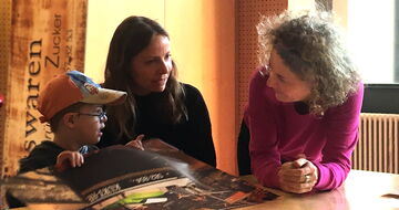 Chariklia Lehmann, Iris Kühnberger und ein kleiner Junge im Gespräch am Tisch